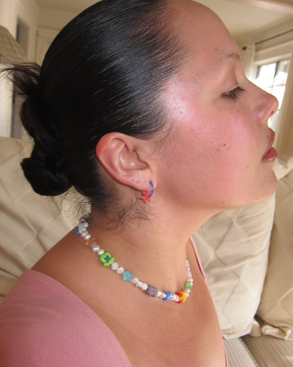 Profile of a woman with slicked-back hair wearing the pastel lucky (ian) charms necklace