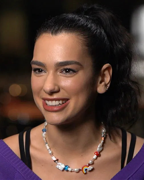 Smiling woman with a high ponytail wearing a custom pearl and colorful charm beaded necklace