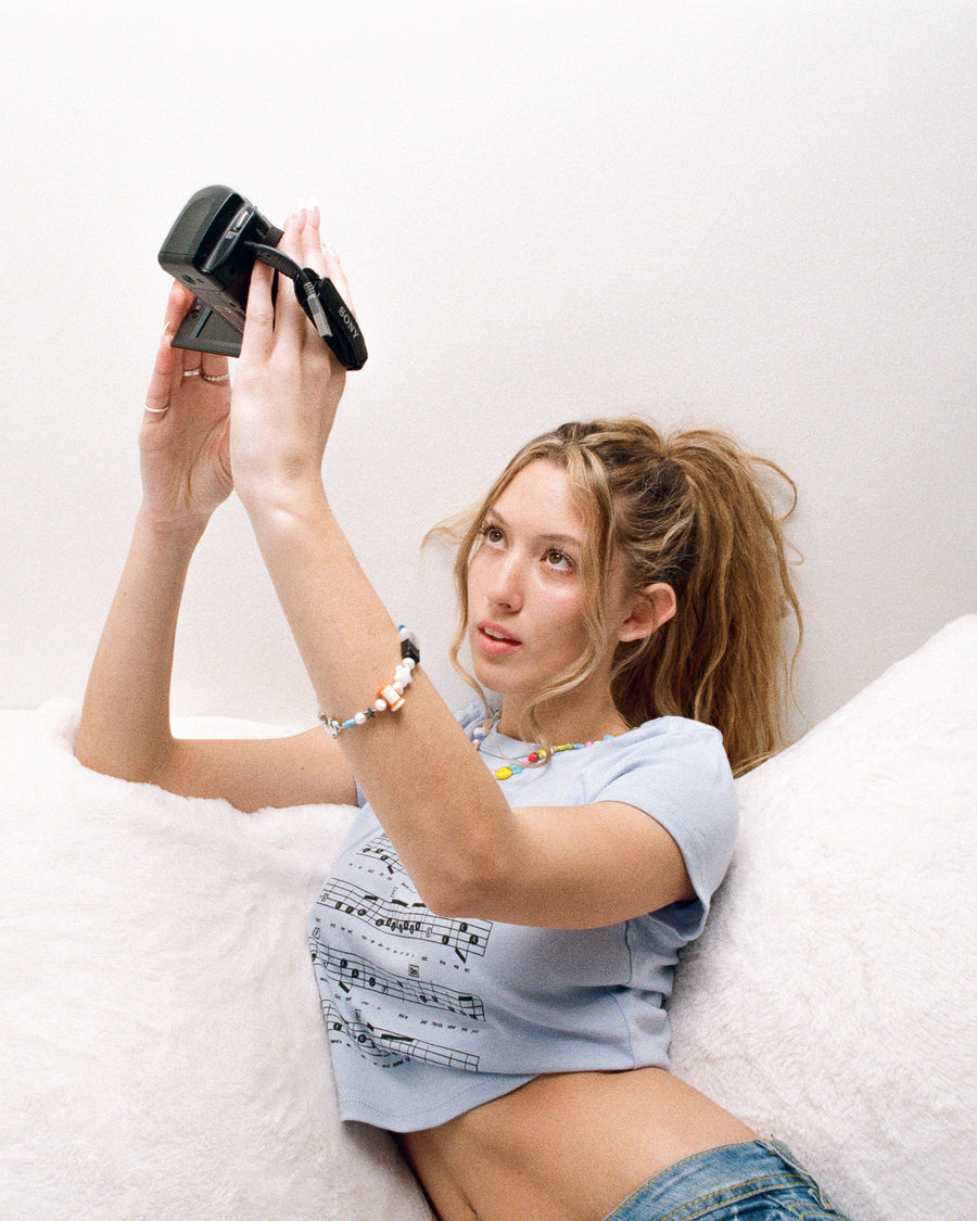 Woman taking a photo with a vintage camera while wearing a beaded bracelet