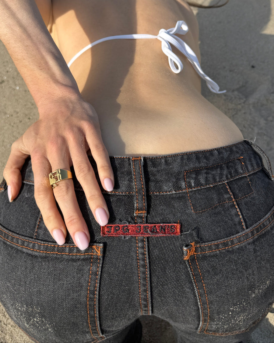 Hand on the back pocket of dark jeans wearing the gold I heart TV intellectual ring