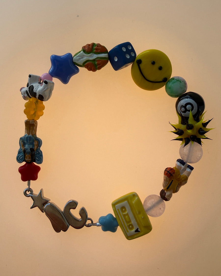 The perfect bracelet does not exi.. with smiley, 8-ball, cassette, spiky ball and blue star beads in warm light