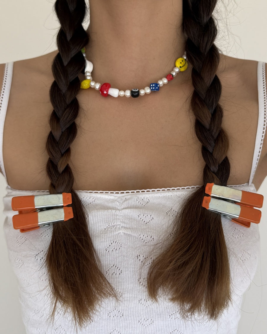 Pearl choker with red, yellow and blue beads and charms worn with braided pigtails – the gabe necklace by Ian Charms