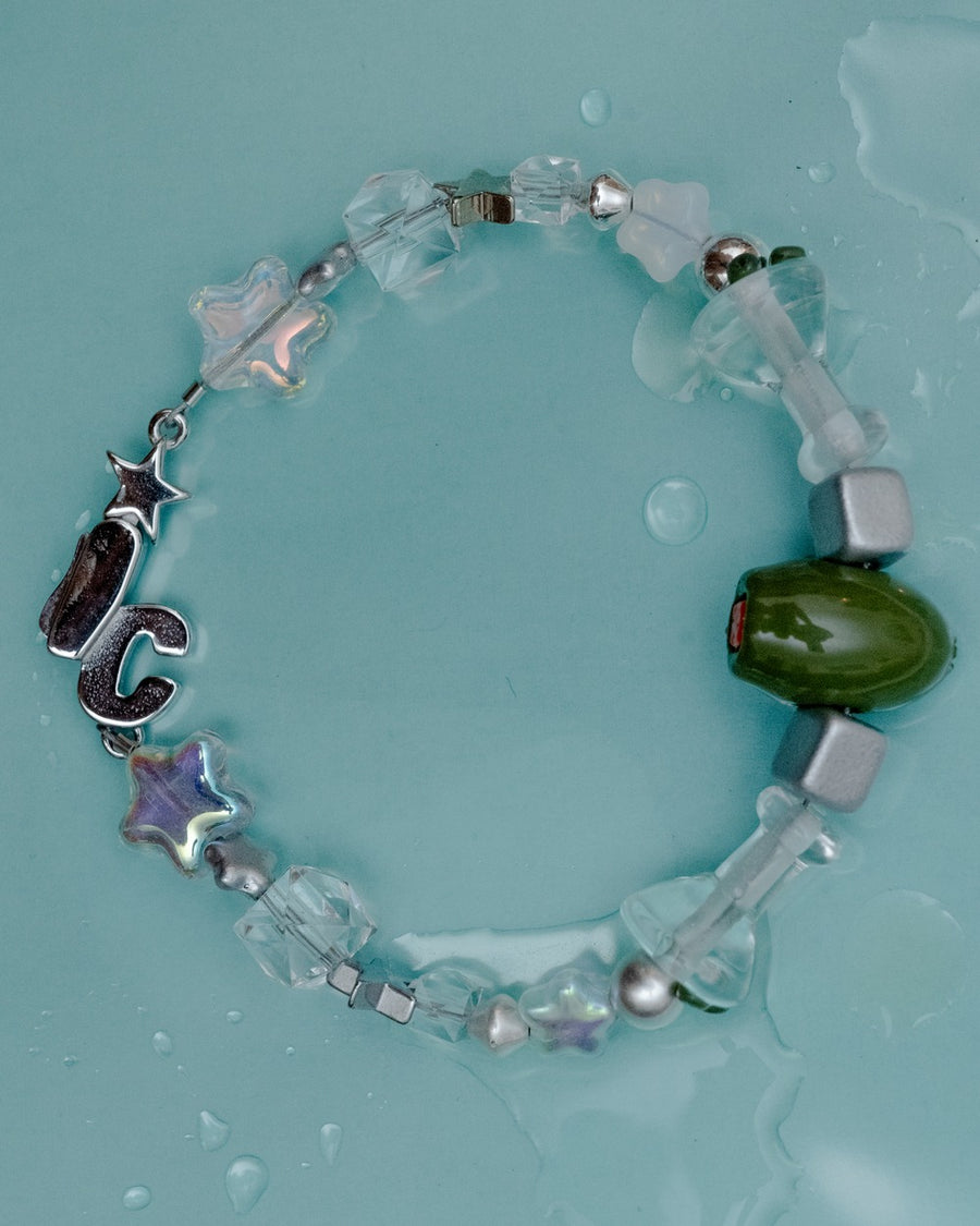 Clear glass martini bead bracelet with silver cubes, a green olive bead and IC clasp on aqua – the usual bracelet by Ian Charms