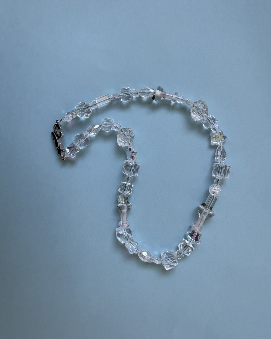 The usual necklace of clear crystal and glass beads coiled on a pale blue background