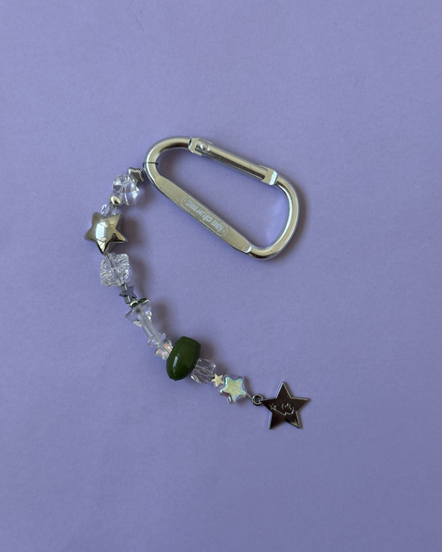 The usual keychain with clear beads, olive bead and black star charm on a lilac background