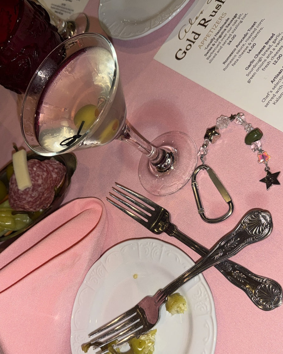 The usual keychain on a pink table with a martini, forks and a Gold Rush menu