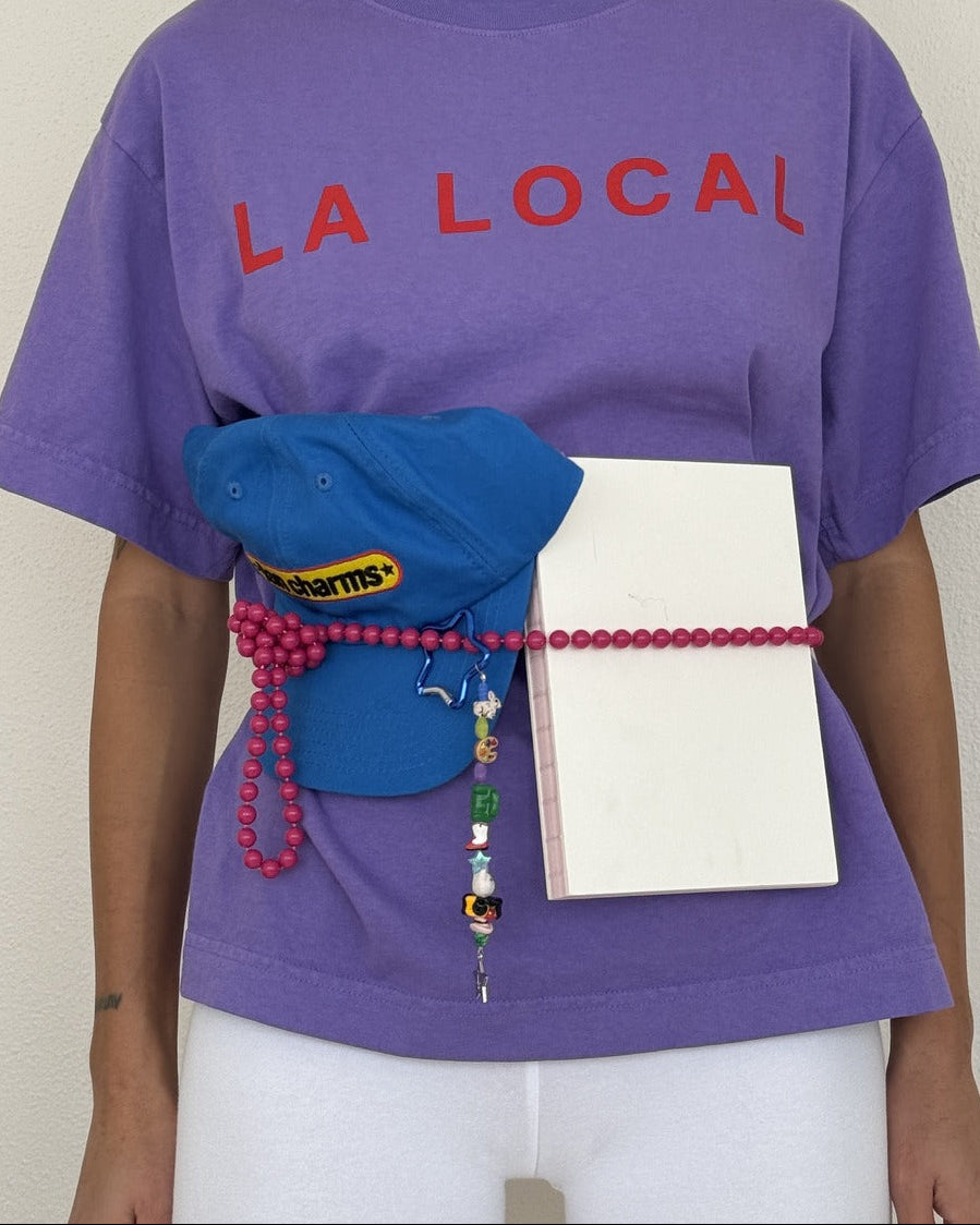 Purple la local tee worn with a blue cap, pink beaded belt and the fb marketplace keychain at the waist