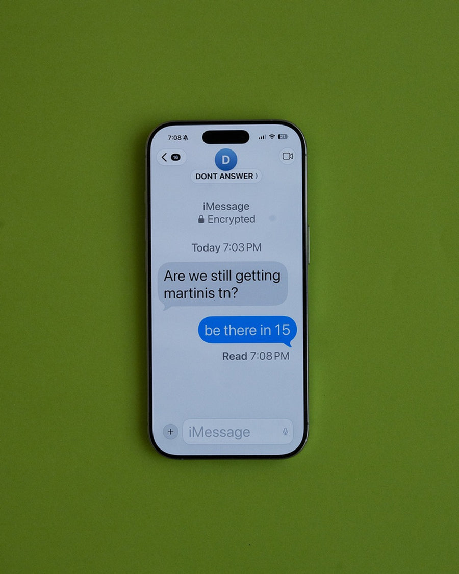 Phone on lime green showing a text conversation about getting martinis