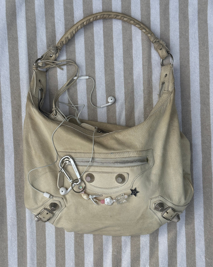 Beige slouchy shoulder bag with the marlee shell and star bead keychain clipped to it