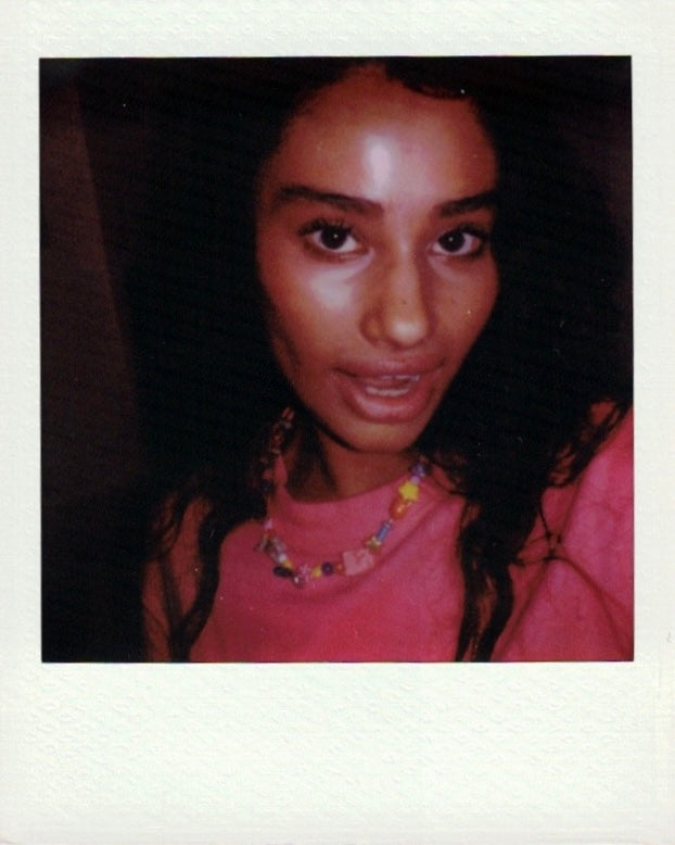 Polaroid of a woman in a pink tee wearing the colorful la beaded necklace
