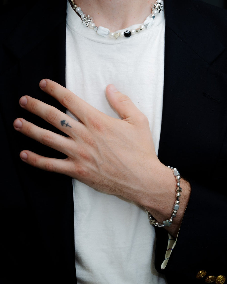 Man in a white tee and black blazer wearing the sloane necklace and a silver beaded bracelet