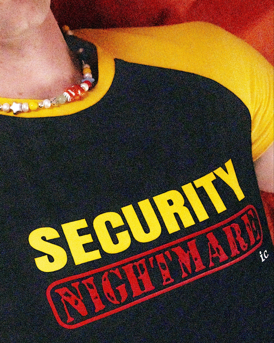 Close-up of the black and yellow securitee nightmare tee worn with a colorful beaded necklace
