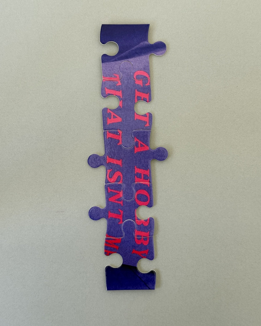 Strip of connected puzzle pieces printed with pink get a hobby lettering