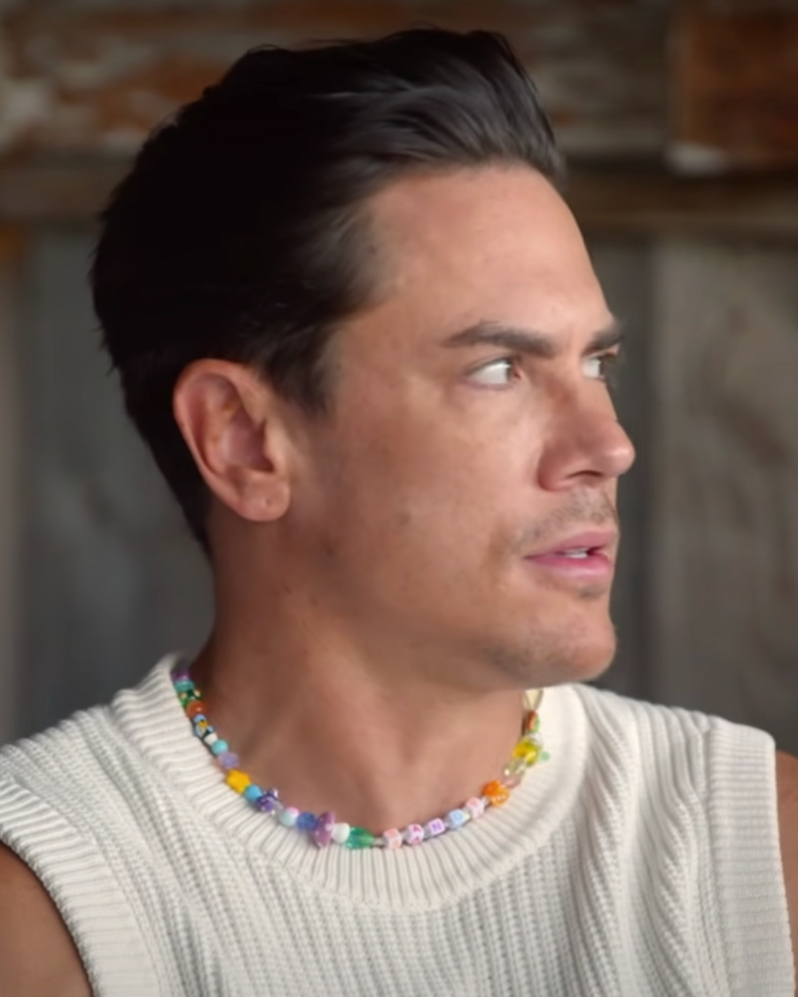 Man in a white knit vest wearing a custom multicolor beaded charm necklace