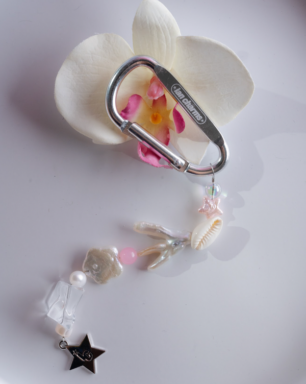 Silver engraved carabiner keychain with shell, pearl and pink beads beside a white orchid – the marlee keychain