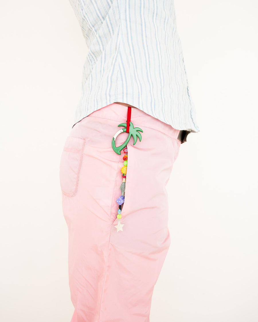 Pink jeans with the club mid palm tree carabiner keychain hanging from a belt loop