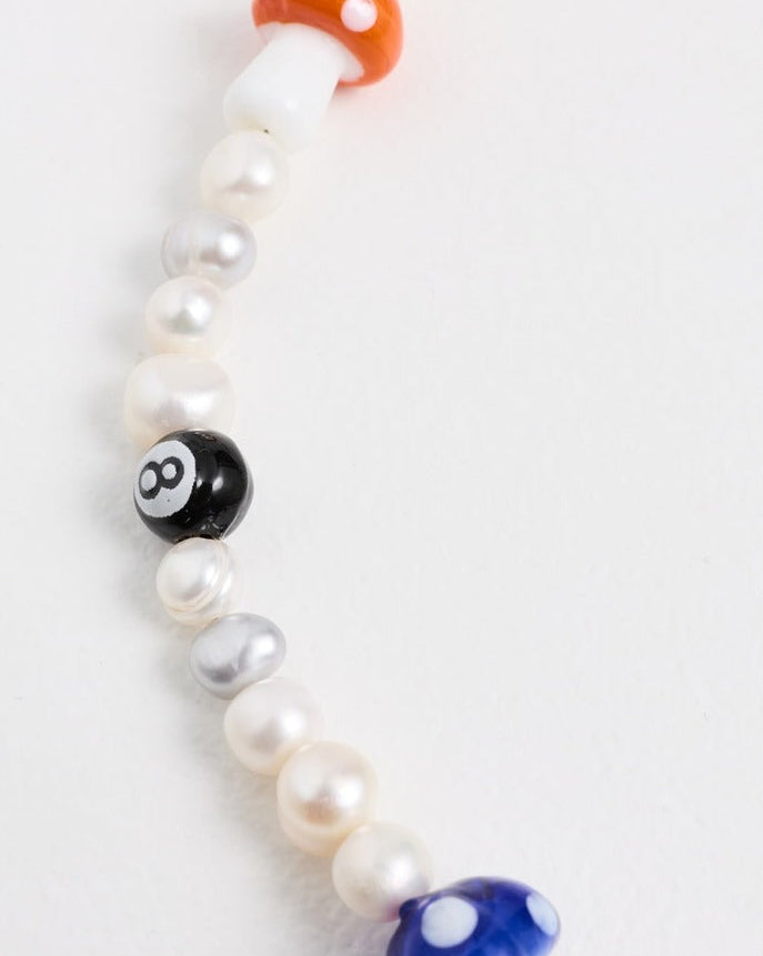Close-up of an orange mushroom bead and a black 8-ball bead on freshwater pearls – the danili necklace
