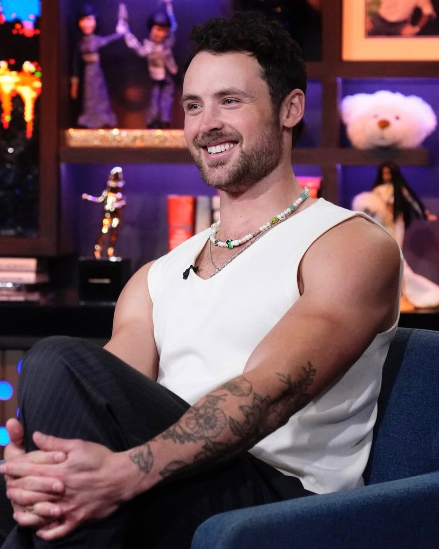 Man in a white tank top on a TV talk show set wearing a custom pearl beaded necklace