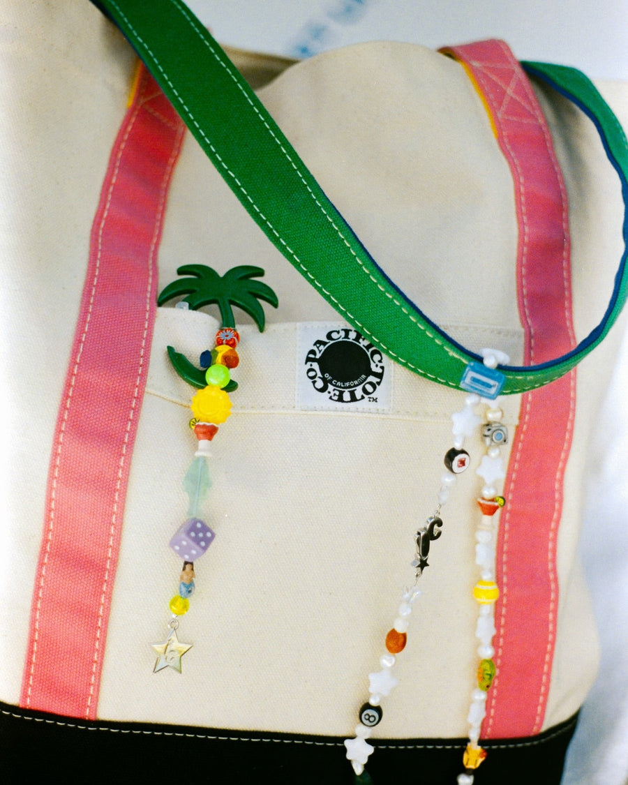 Canvas tote with the club mid palm tree keychain clipped to its strap