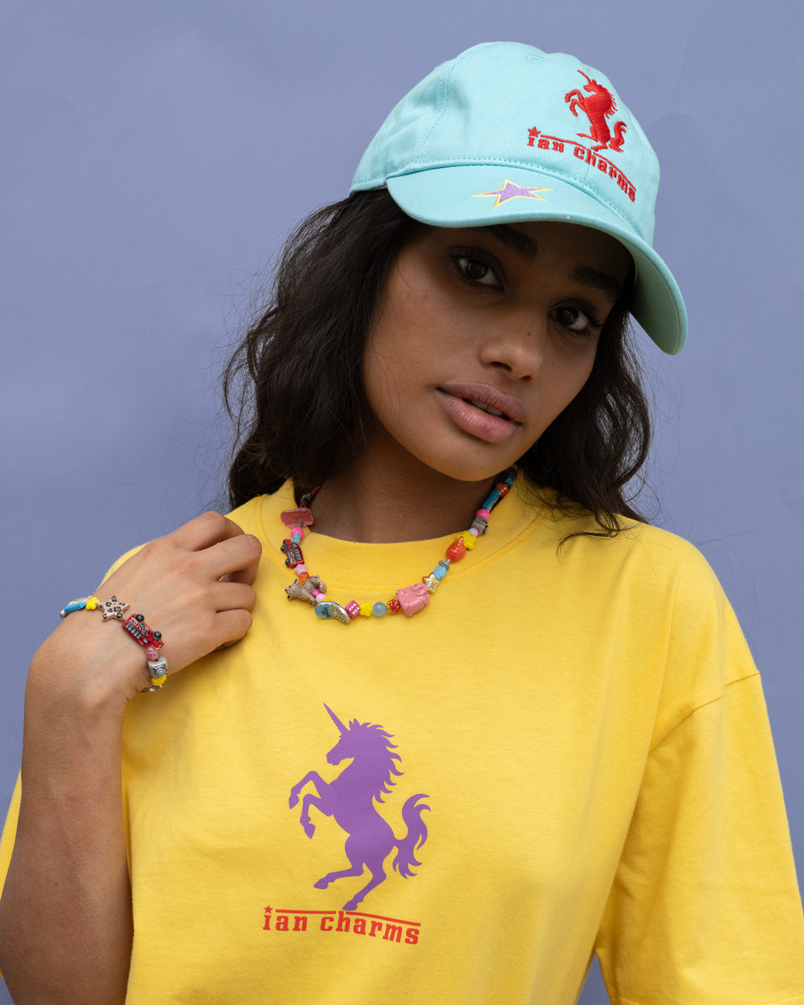 Woman in a light blue cap and yellow pony soprano tee wearing the colorful la necklace and LA bracelet