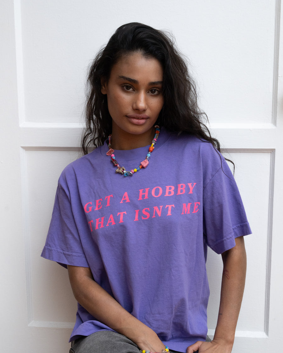 Woman in the purple get a hobby tee wearing a colorful beaded necklace