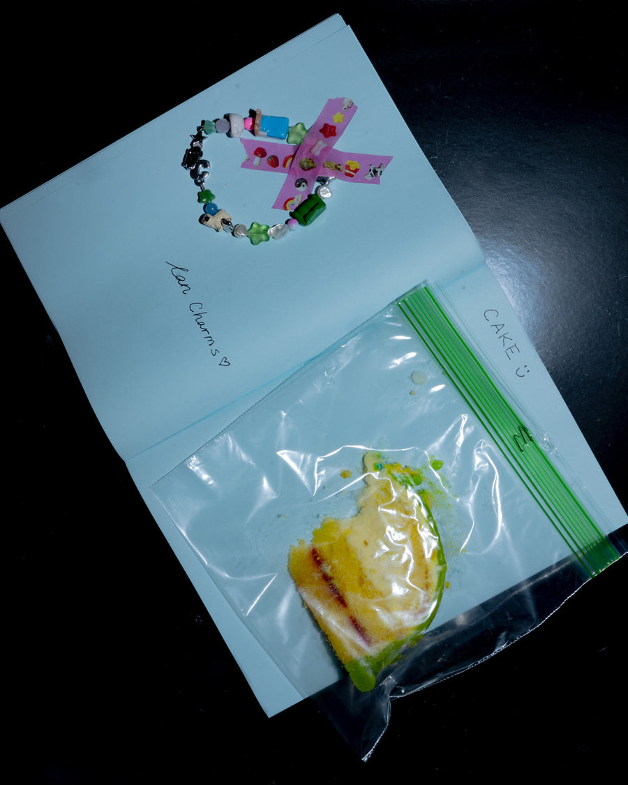 Notebook page with a beaded bracelet taped down and a ziplock bag of candy on black