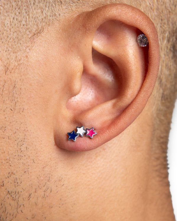 Close-up of an ear with a stacked trio of colorful star stud earrings – the lukas studs