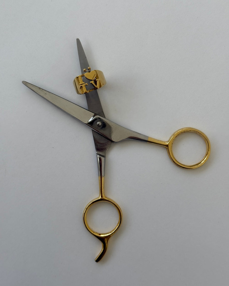The intellectual I heart TV gold ring resting on a pair of gold-handled scissors
